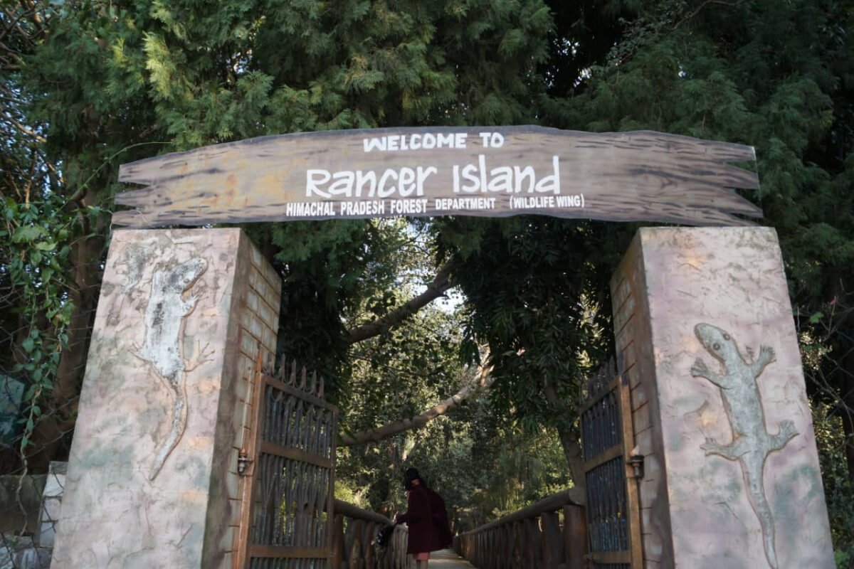 The Himachal Pradesh Forest Department welcome gate on Rancer Island, with a visitor walking through onto the island path