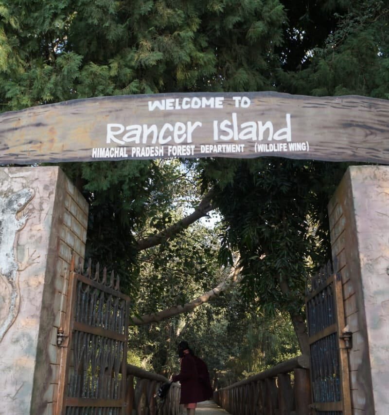 The Himachal Pradesh Forest Department welcome gate on Rancer Island, with a visitor walking through onto the island path